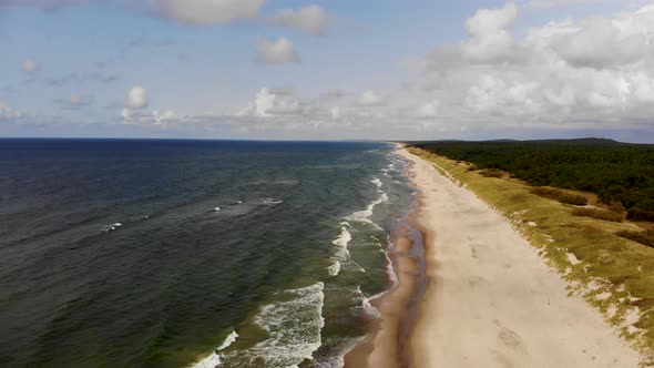 AERIAL: Flying very high over sunny Baltic Sea beach 