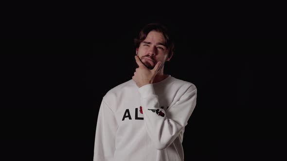 Trendy Young Man rubbing chin and thinking, wide, black background