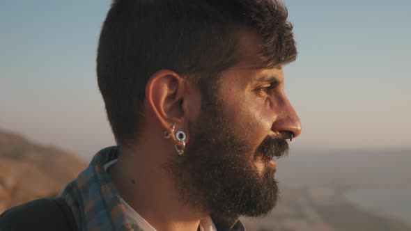 A young bearded man walking at sunset