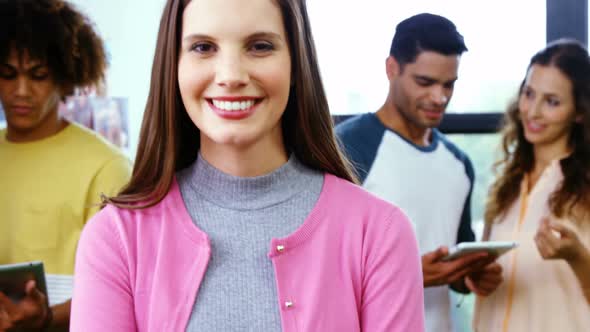 Smiling graphic designer standing with arms crossed while colleague discussing 