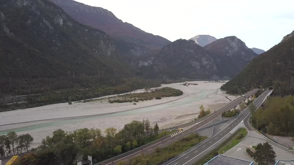 Aerial view of freeway interstate road in italian alps with fast moving traffic and rural green