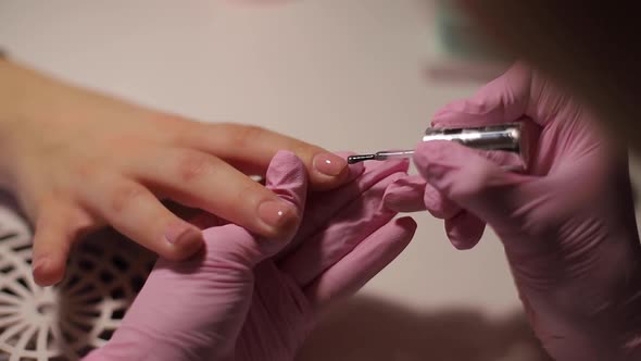 Closeup of Women Paints Nails. Manicure Nail Art. Female Works in Pink Gloves. Close Up of Woman's