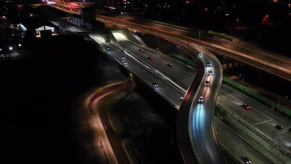 Aerial flyover traffic jam interchange road at night, drone shot top down view roadway intersection
