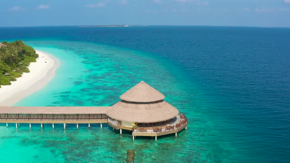 Aerial View of the Stilt Hut with Palm Thatch Roof with Turquoise Indian Ocean on the White Sand