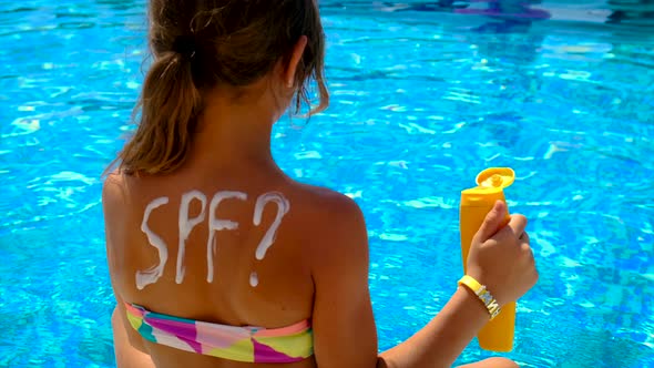 A Child Smears Sunscreen By the Pool