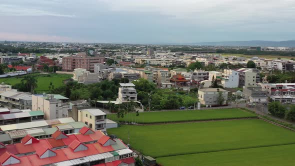 Aerial Drone Footage of Urban Agriculture with Grid Farm Land and Rice Paddy Field and residential h