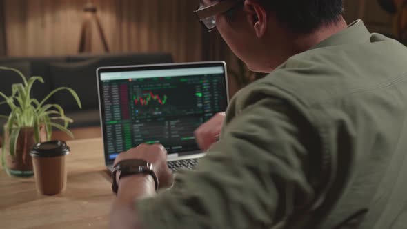 Man Trader Sitting In A Wheelchair And Stretching While Trading Data Index Chart Graph On Laptop