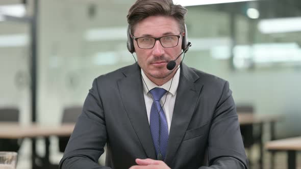 Middle Aged Businessman with Headset Looking at Camera 