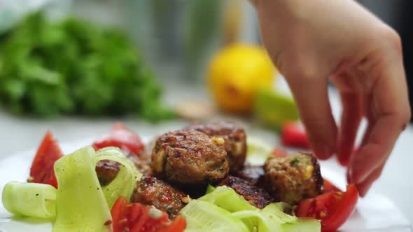 Anonymous person serving meatballs on ceramic plate