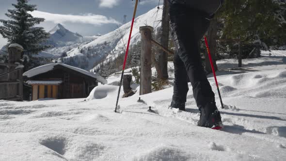 Man Ski Touring Through Forest Towards Building On Mountain