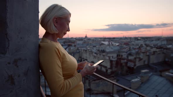 Middle-aged Woman with Smartphone on Roof