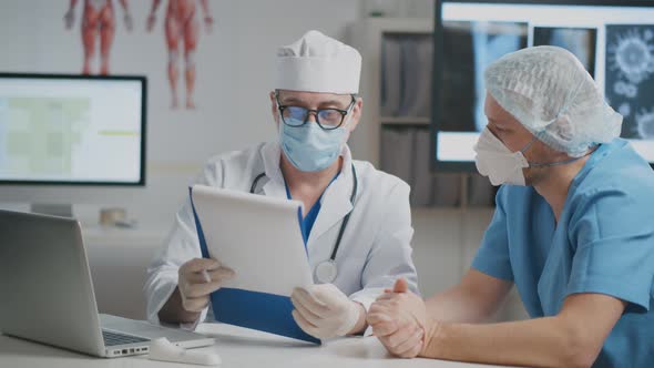 Nurse and Doctor Having Conversation About Covid19 Virus in the Hospital Looking at Clipboard.