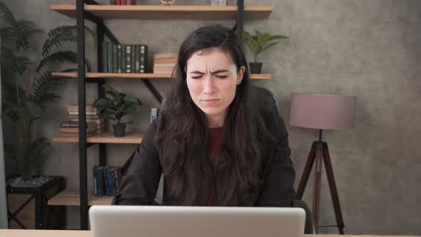 Disgusted Brunette Woman. Female Office Worker Watches To Laptop Screen and Sees Something