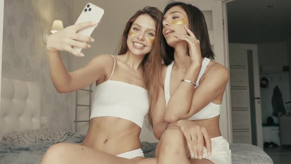 Two young beautiful smiling women with patches under their eyes posing indoors