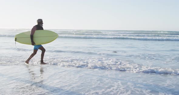 Happy african american couple running with surfboards on sunny beach