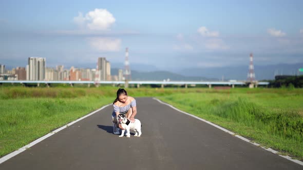 Woman embracing dog squatting on pathway in summer