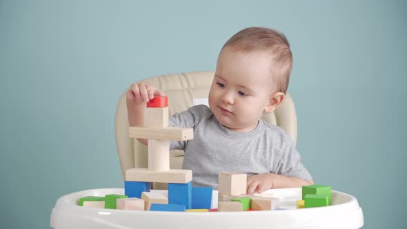 A joyful baby of 15-25 months is learning to play with a wooden block constructor.