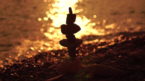 Balanced Pebbles Pyramid on the Beach on Sunny Day and Clear Sky at Sunset