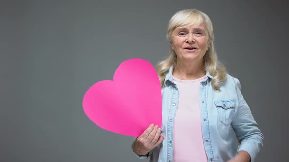 Happy Elderly Lady Making Kiss Holding Pink Heart, Valentines Day, Healthcare