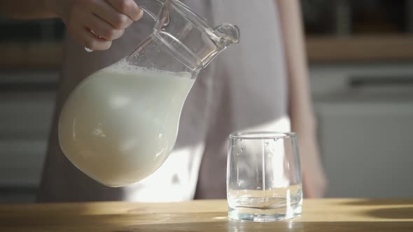 Slow Motion Pouring Milk in Glass on Wooden Table