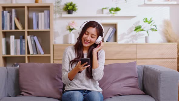 Young women listening to music in headphones and dancing energetic and rhythm at couch. Attractive A