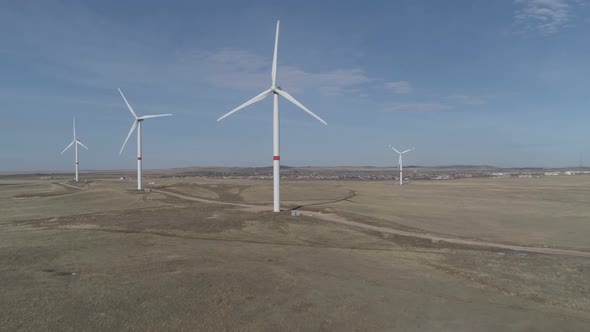 Blades of a Large Wind Turbine in a Field Against a Background of Cloudy Blue Sky on the Horizon