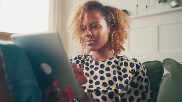 Satisfied African American Woman with Digital Tablet Resting at Home on Sofa