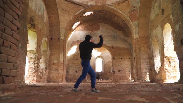 Man boxer in the hood trains beats in an abandoned building. Shadow Boxing on a beautiful Sunlight