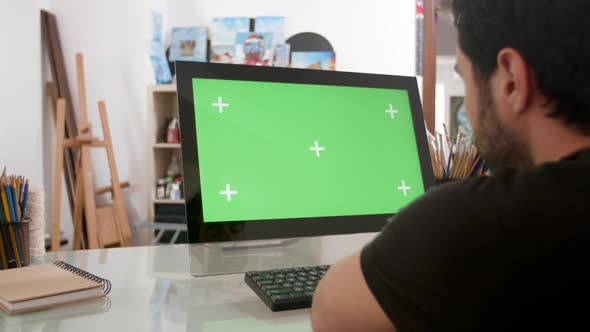 Bearded Man Looking at a Green Screen on His Computer
