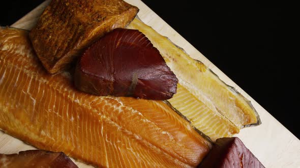 Rotating shot of a variety of delicious, premium smoked meats on a wooden cutting board 