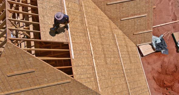 Aerial Top View of Construction Worker Nailing Roof Panels