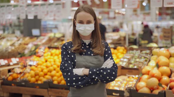 Portrait of a Female Worker in an Apron and Protective Mask Against a Background of Vegetables and