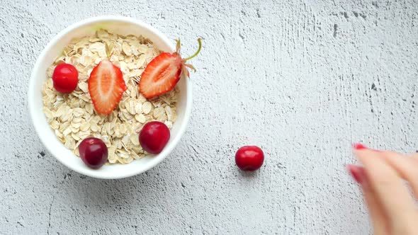 Detail Shot of a Kitchen Table with a White Cup of Oatmeal and Strawberries and a Hand That Lays