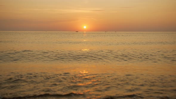 The Boat Sails in the Distance Against the Backdrop of the Sunset