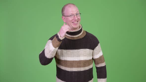 Happy Mature Bald Man with Turtleneck Sweater Giving Thumbs Up