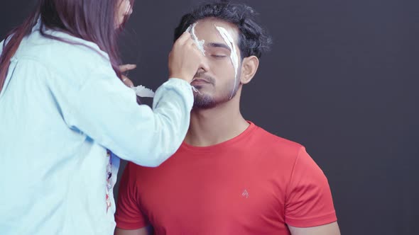 Make up artist making a scary mask for Halloween night on man's face