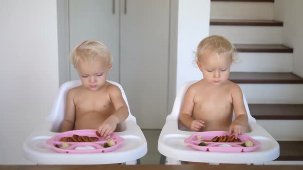 Mom Serving Healthy Plant Based Lunches to Her Twin Children Sitting in High Feeding Chairs