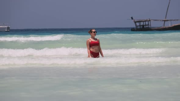 Young Woman in Red Swimsuit Resting and Bathing Into the Ocean on Paradise Beach