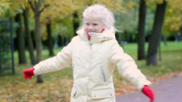 Little Girl Having Fun Spinning Outdoor in Autumn Orange Park