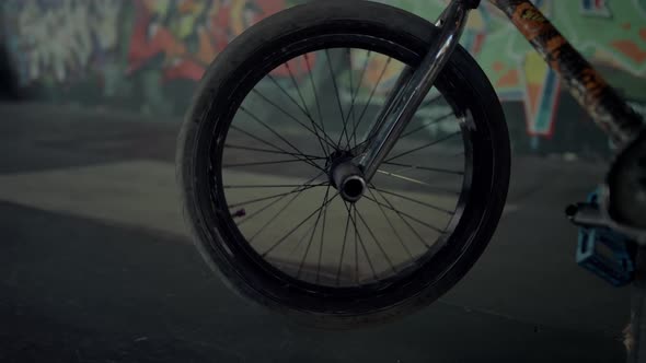 Bmx Bicycle Wheel Spinning at Skatepark with Graffiti Wall