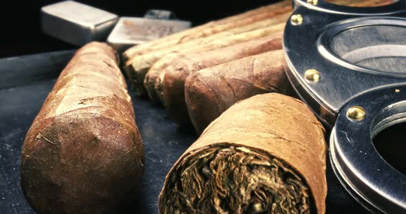 Closeup of cigars, lighter and cutter in humidor.