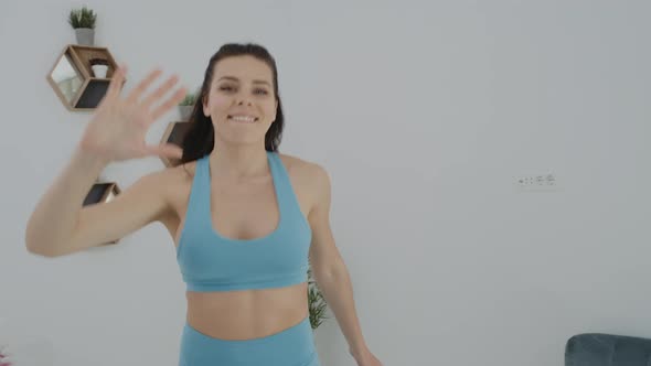 Athletic smiling woman looking at camera and doing high five after workout at home.