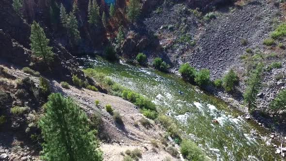 Aerial view of people in kayaks navigating a white-water river in a steep and rugged canyon