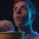Young man at the cinema, he is eating popcorn and watching a movie - VideoHive Item for Sale