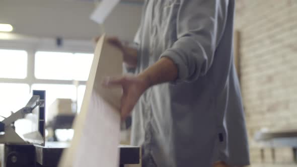 Young Carpenter Trimming Wood Board on Jointer and Checking Surface