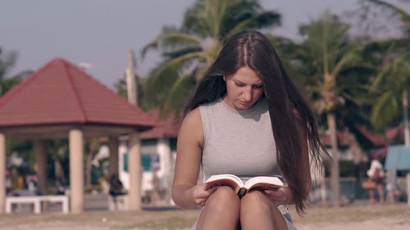 Pretty Lady with Long Hair Waved By Wind Sits and Reads