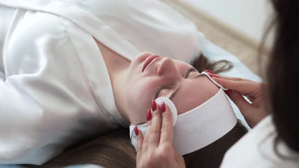 Back View of Cosmetologist Doctor Wiping Woman Face Uses Cotton Pads After Peeling Procedure