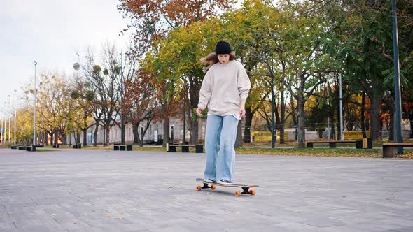 Front View of a Young Teenage Girl Performing Tricks While Riding a Longboard