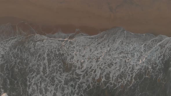 Ocean waves crashing on Ponta da Calheta beach, Porto Santo island. Aerial top-down rising