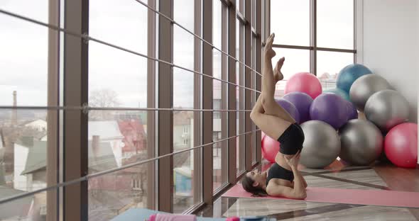 Athletic Woman Stretching on a Mat in a Fitness Studio